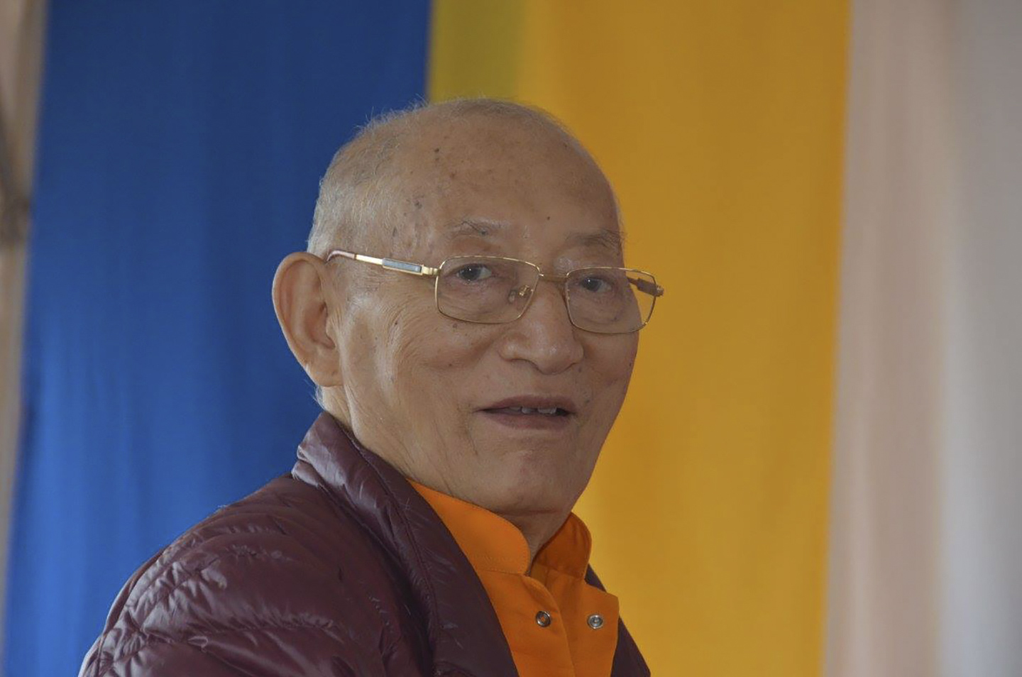 A Buddhist monk in front of aqua and orange cloth