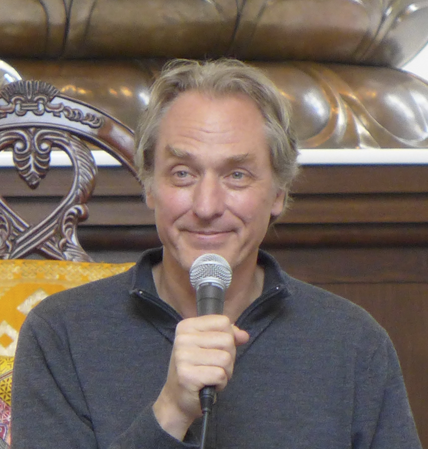 Man in a grey sweather holding a microphone