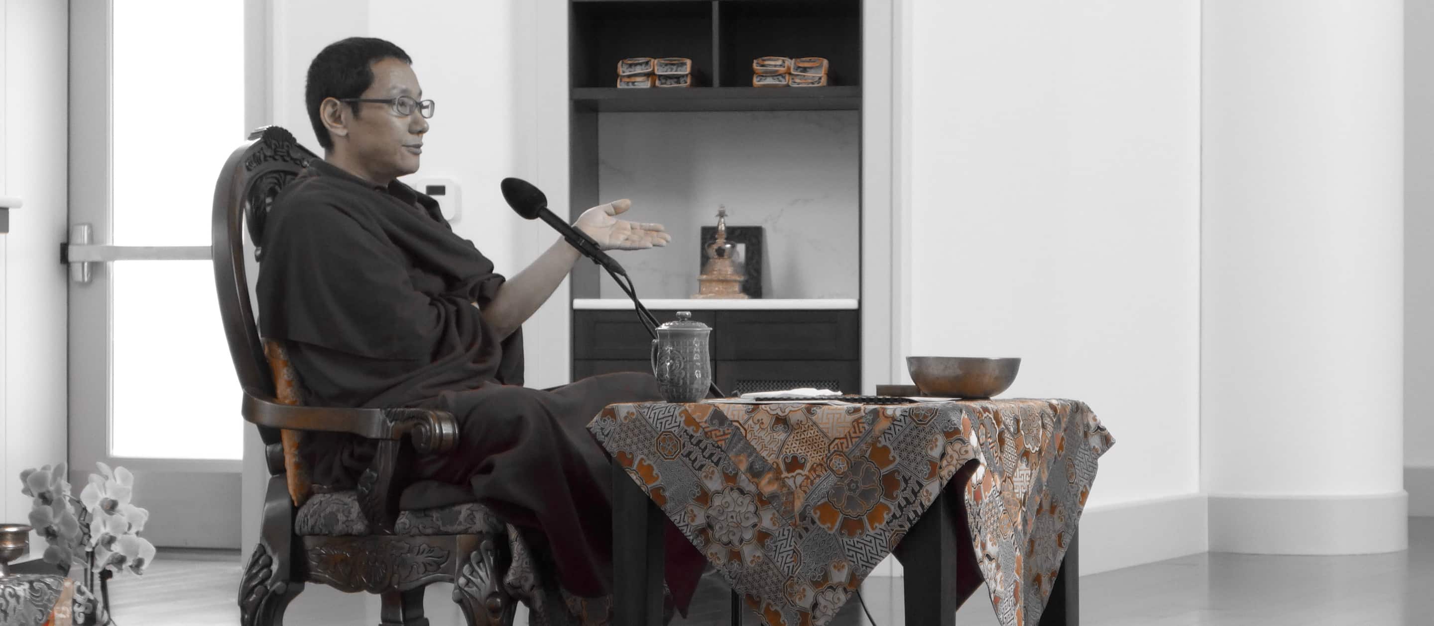 Buddhist lama at a table speaking through a microphone