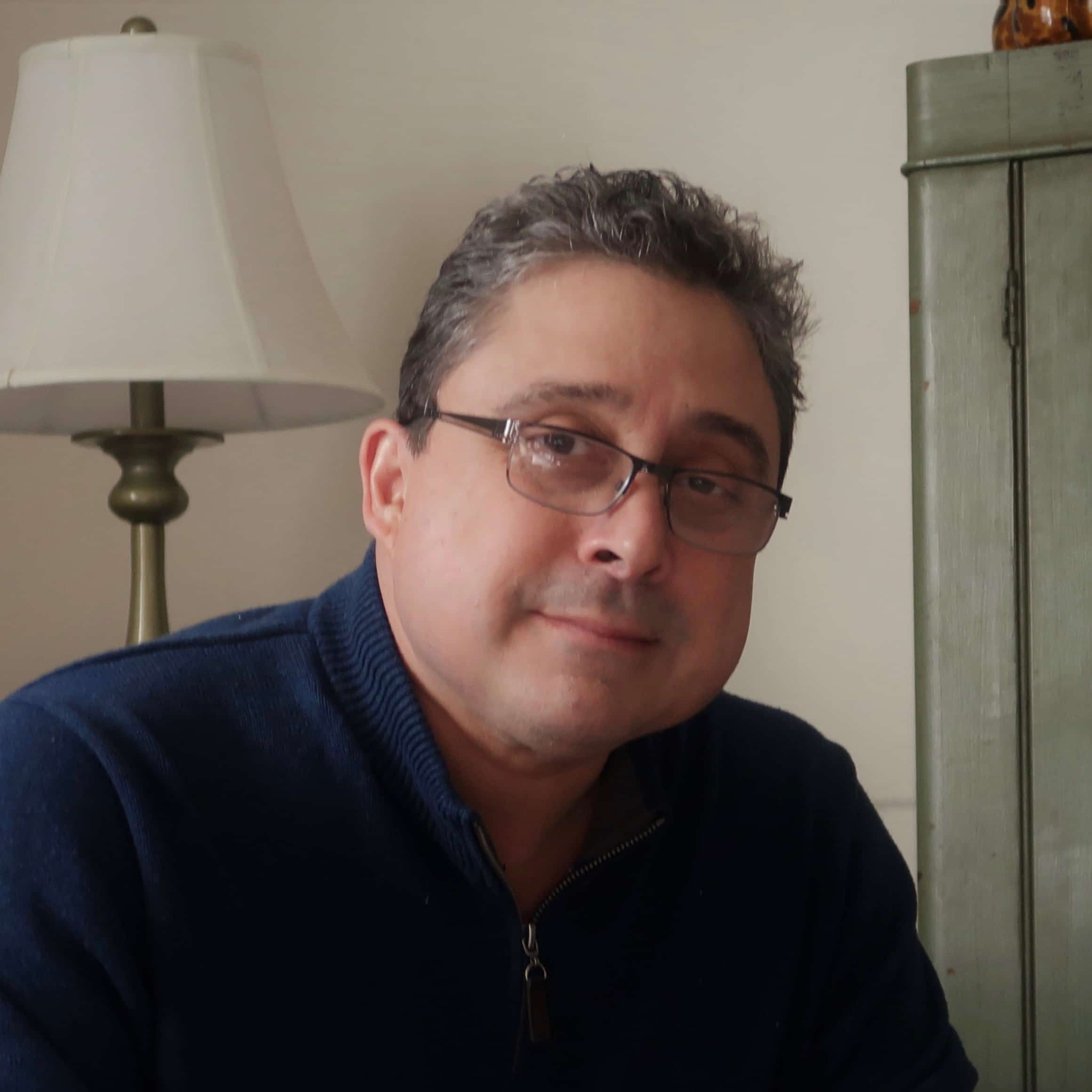 Man wearing glasses and a navy pullover sweater